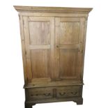 A reproduction pine wardrobe with moulded dentil cornice above panelled doors enclosing hanging