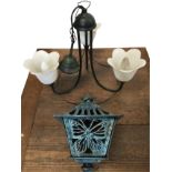 A wrought iron verdigris patinated hanging light with three scrolled branches supporting petal
