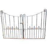 A pair of wrought iron driveway gates with scrolled finials to square cornerposts, the concave