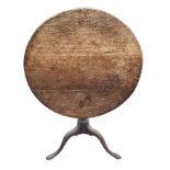 A circular nineteenth century oak snap-top table, raised on turned column with tripartite legs on