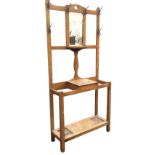 An Edwardian oak hallstand with central bevelled mirror above a rounded shelf within a frame mounted