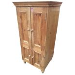 A pine cupboard with moulded cornice above four knobbed panelled doors enclosing shelves, raised