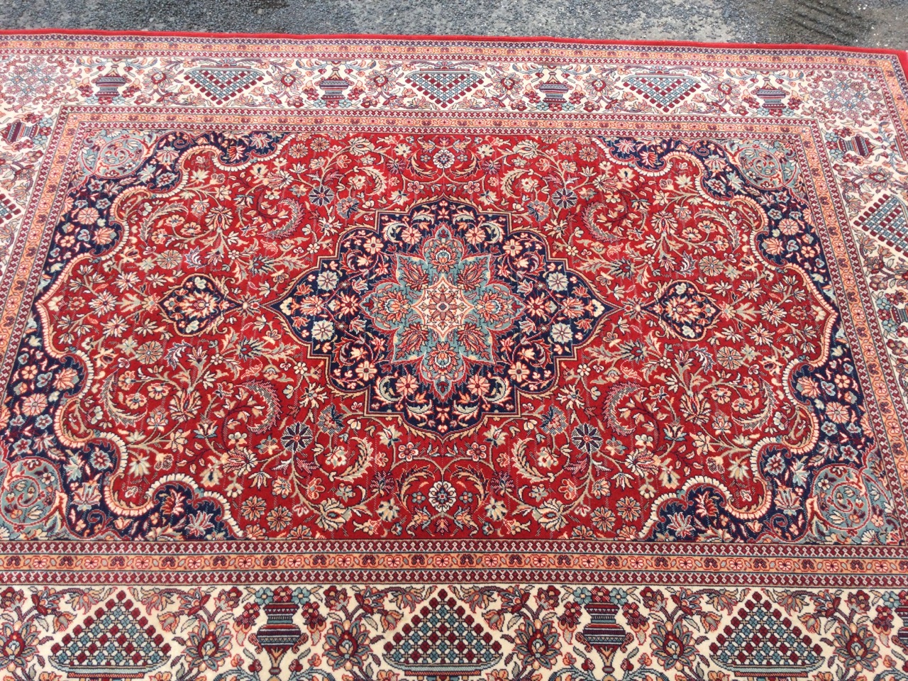 An Indian rug woven with busy red floral field framing a central scalloped blue floral medallion - Image 2 of 3