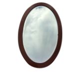 An Edwardian oval mahogany framed mirror inlaid with boxwood stringing, the plate bevelled. (21.