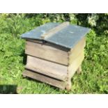 A tapering dovetailed Thorne beehive with galvanised roof, raised on rectangular angled legs. (