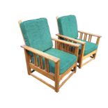A pair of oak arts & crafts style armchairs with folding slatted backs and loose cushions, having