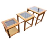 A nest of three 70s coffee tables with rectangular glass panels to moulded tops, raised on square