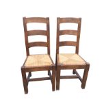 A pair a contemporary oak ladderback kitchen chairs, the curved back rails above rush seats, on