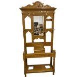 A late Victorian carved and scumbled hallstand, the scrolled crest with lion mask above a bevelled