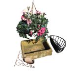 A rectangular faux stone trough; a hanging basket with artificial flowers; and two garden wall