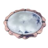 An oval 1950s mirror with bevelled plate, having chrome flowerhead mounts within a pink bevelled