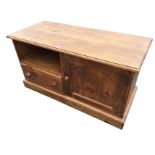 A pine cabinet with moulded top above an arched panelled cupboard flanked by an open compartment and