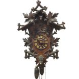 A German carved cuckoo clock with applied log & leaf decoration to case, having roman chapters to
