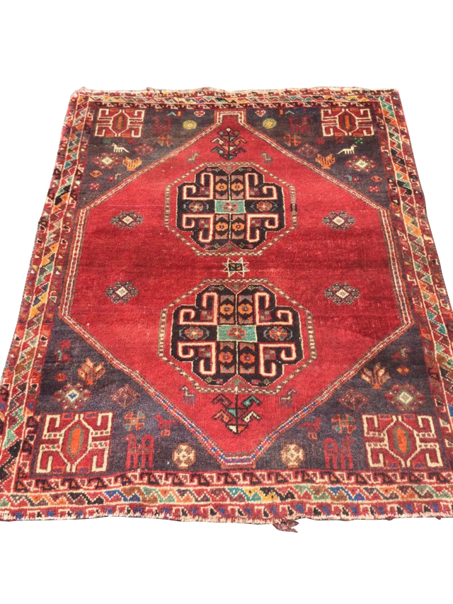 An oriental rug woven with two octagonal hooked medallions on red field having charcoal grey