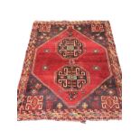 An oriental rug woven with two octagonal hooked medallions on red field having charcoal grey