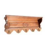 A late Victorian carved coat rack, having shelf on shaped supports above a scroll carved panel, with