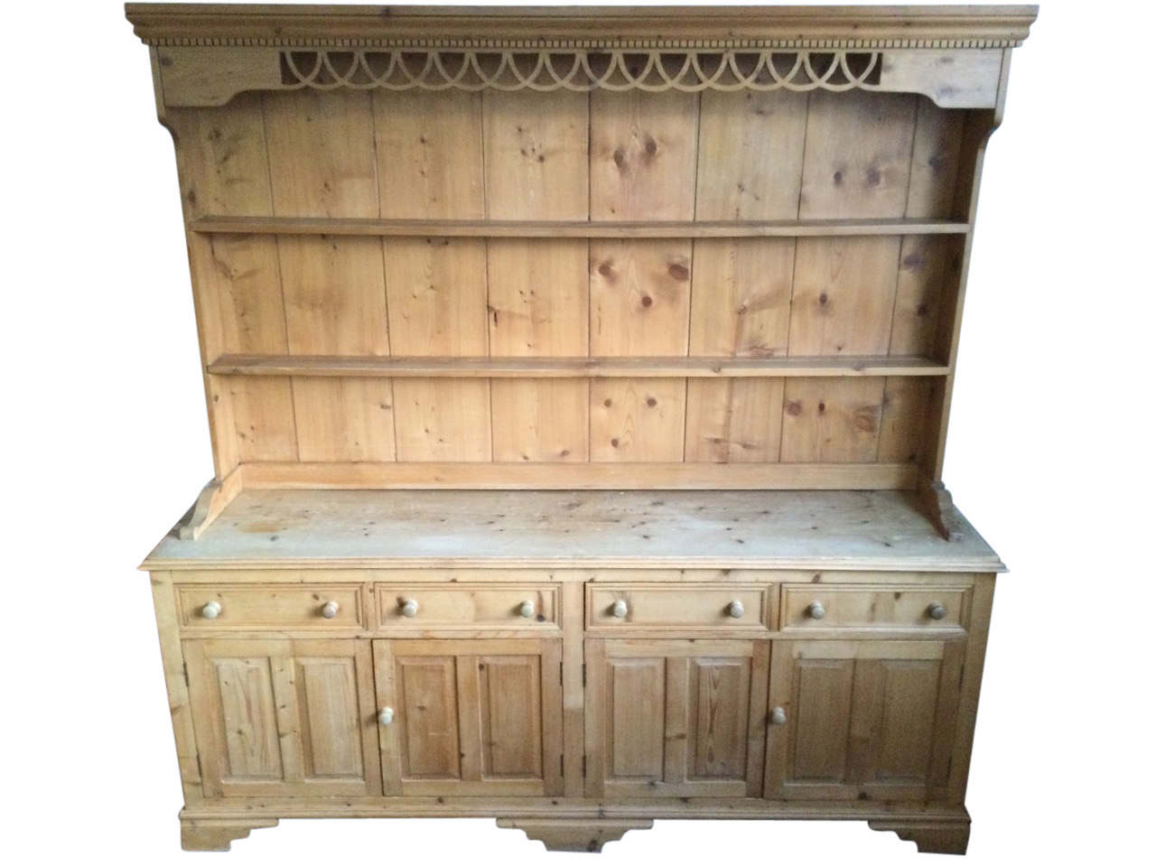 A pine dresser, the delft rack with moulded dentil cornice above a pierced fretwork apron, having