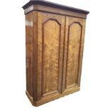 A Victorian pitch pine wardrobe with moulded cornice above canted panelled doors enclosing a