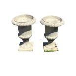 A pair of resin urns with lozenge moulded overhanging rims on lobbed & fluted bases with square