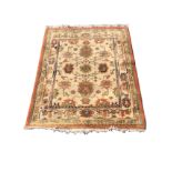 A rectangular Indian rug woven with vases of flowers framing a floral medallion on fawn ground,