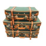 A set of three new unused canvas suitcases with leather and brass mounts, all with keys. (3)