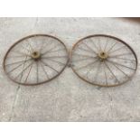 A pair of large agricultural wheels with channelled flat rims framing two sets of spokes with