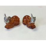 A pair of amber style rabbits with silver plated mounts, the bodies with flaked inclusions having