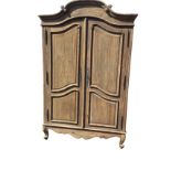 A French oak armoire with arched scroll carved cornice above fielded panelled doors enclosing