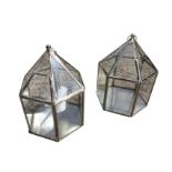 A pair of hanging hexagonal glass lanterns supported by chains, the enclosures with chromed