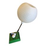 A 50s novelty golf tablelamp, with angled iron club supporting a golf ball shade on a green plinth