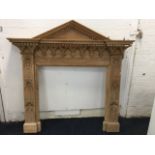 A gothic style carved pine chimneypiece with triangular dentil pediment above a breakfront