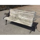 A cast iron garden bench with slatted back & seat on pierced scrolled ends, having lionmask roundels