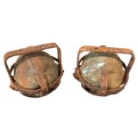 A pair of bronze dolls head moulds, the heads swinging in metal gimbal type cages. (6in) (2)