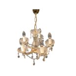 A hanging glass chandelier suspended by chain from brass ceiling rose, with baluster shaped column