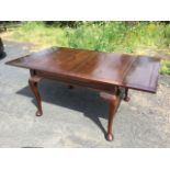 A C20th mahogany dining table, the rectangular draw-leaf panelled top on plain rails, raised on