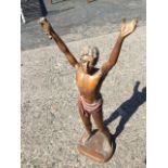 A carved wood figure of a young man wearing loincloth with raised arms, standing on plinth. (25.