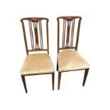 A pair of Edwardian art nouveau mahogany chairs with boxwood strung backs decorated with oval