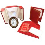 A leather cased Cartier travel clock with oval tortoiseshell effect brass frame on easel stand,