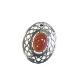 An oval Scottish silver brooch with pierced celtic style border, claw set with cabouchon agate above