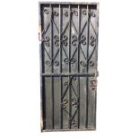 A rectangular wrought iron garden door, the back with wood panel, the square metal frame with