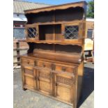 An oak dresser, the back with moulded cornice and shaped apron above open shelves flanked by