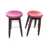 A pair of circular upholstered stools on tapering legs joined by metal rod stretchers. (2)