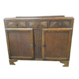 A 1930s oak sideboard with rectangular moulded top above three floral chisel carved frieze