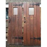 A pair of planked oak doors mounted with decorative scrolled ironwork & studding, each fitted with