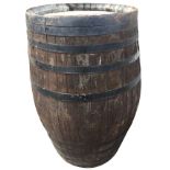 A massive bulbous oak whisky barrel, the staves bound by nine riveted metal strap bands. (50.75in)