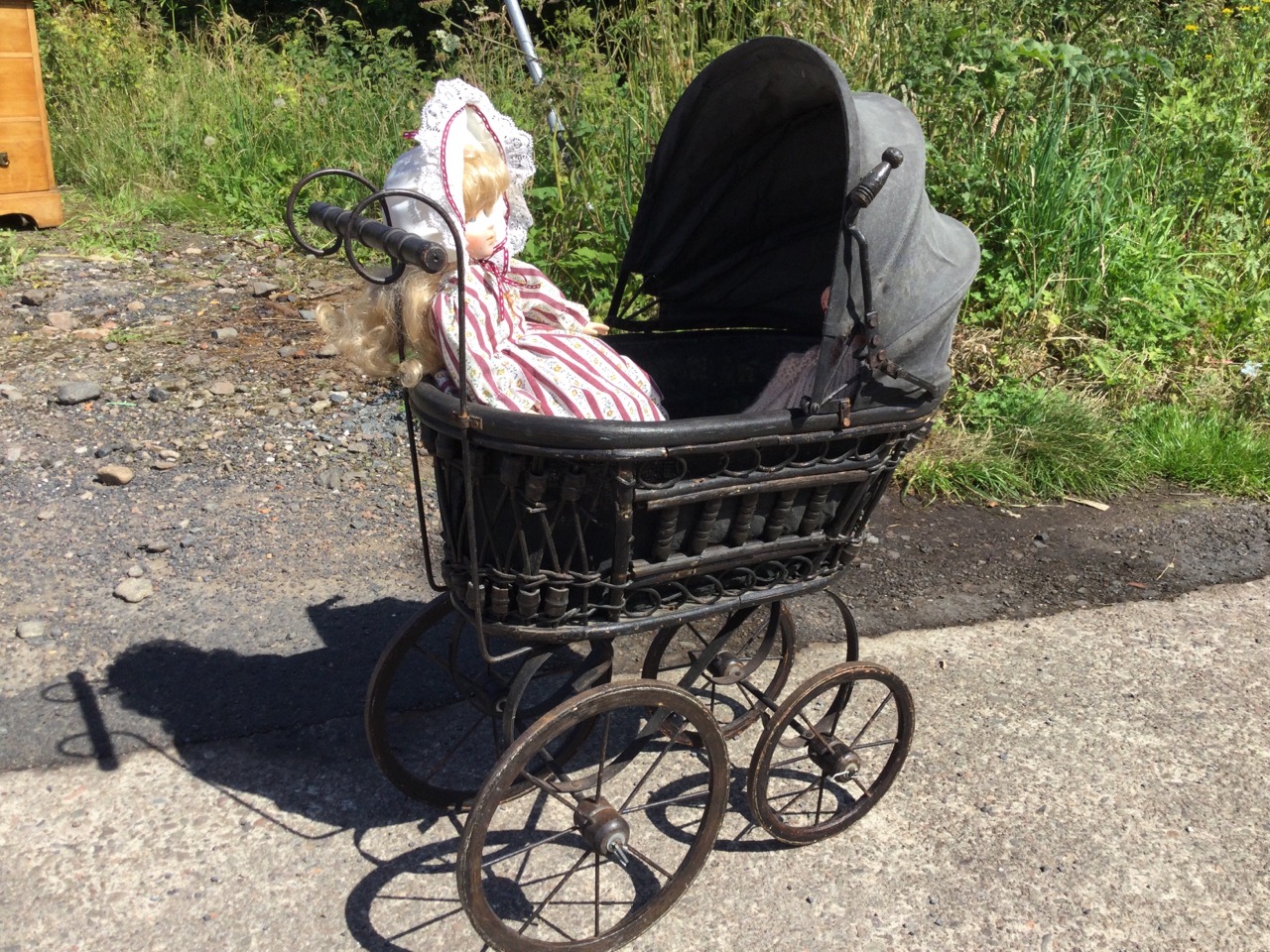 A compostion jointed doll and a porcelain headed doll with glass eyes, in a cane framed pram with - Image 3 of 3