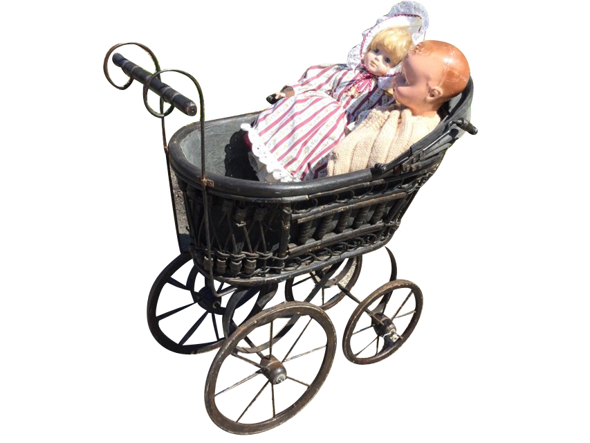 A compostion jointed doll and a porcelain headed doll with glass eyes, in a cane framed pram with