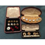A kidney shaped boxed set of six dress studs with circular mother-of-pearl panels set with emeralds;