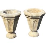 A pair of octagonal carved stone urns, the tapering pots with gothic panels beneath chamfered