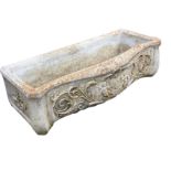 A rectangular composition stone trough of serpentine outline embossed with cherubs and foliate